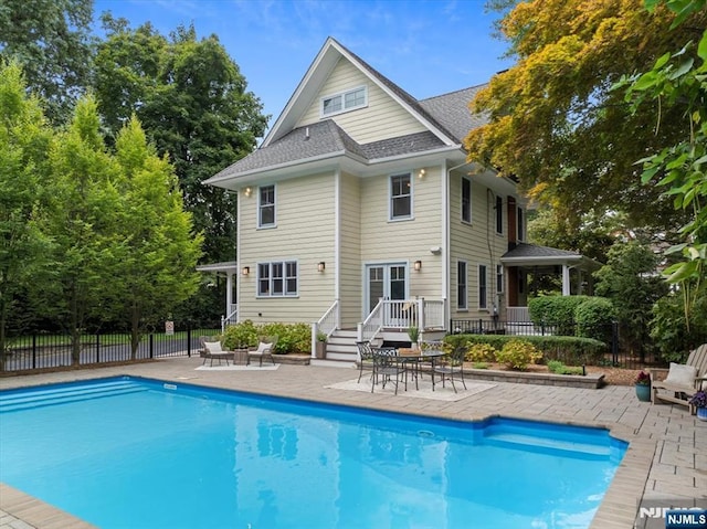 back of house with a shingled roof, fence, a fenced in pool, and a patio