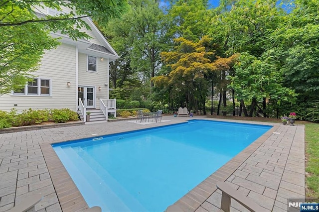 outdoor pool with french doors and a patio