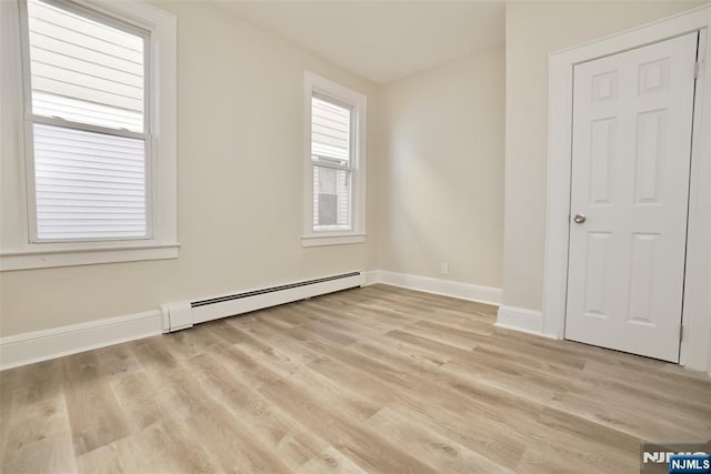 spare room with light wood-style flooring, a baseboard heating unit, and baseboards