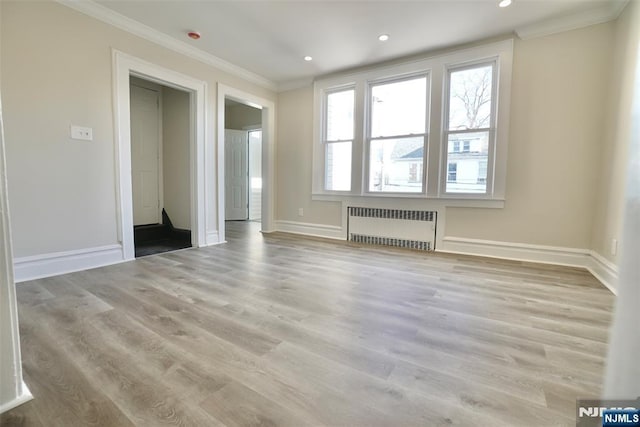 unfurnished room with ornamental molding, radiator, baseboards, and wood finished floors