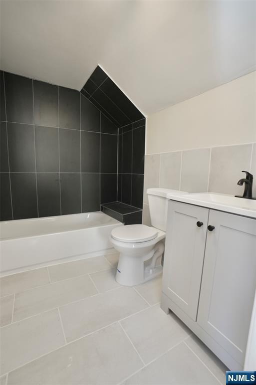 full bath featuring toilet, a bathing tub, tile patterned flooring, vaulted ceiling, and walk in shower