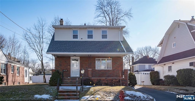 view of front of property featuring roof with shingles, a chimney, fence, and brick siding