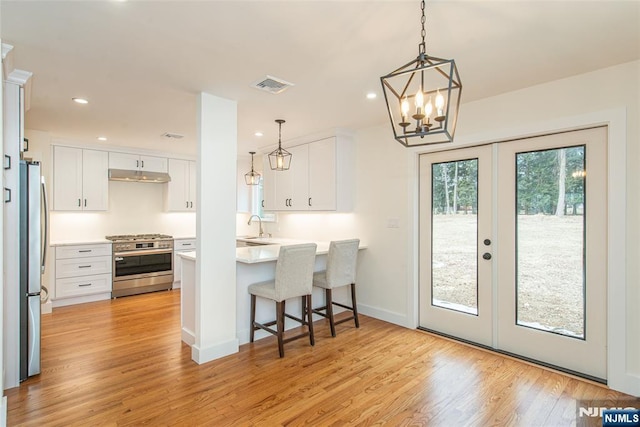 kitchen with stainless steel appliances, visible vents, light wood-style floors, white cabinetry, and under cabinet range hood