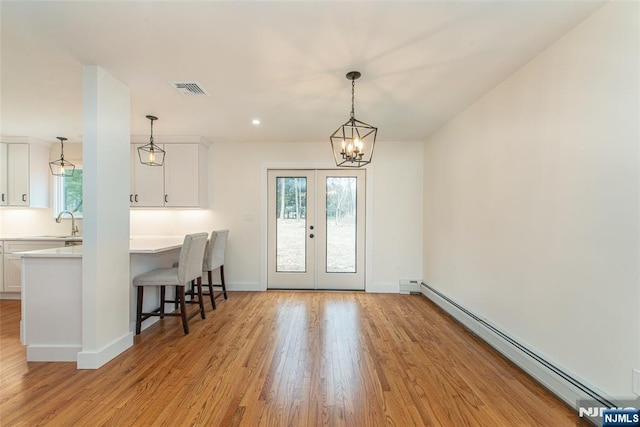 interior space with french doors, light wood finished floors, visible vents, a baseboard heating unit, and baseboards