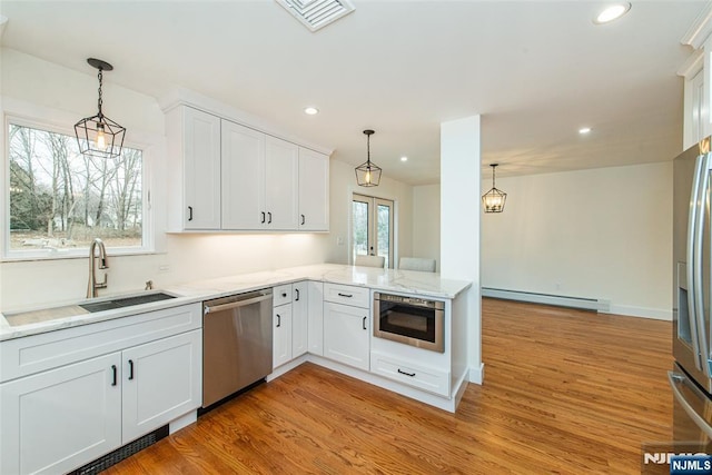 kitchen featuring visible vents, baseboard heating, appliances with stainless steel finishes, a sink, and light wood-type flooring