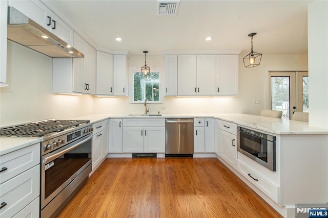 kitchen featuring under cabinet range hood, a peninsula, a sink, visible vents, and appliances with stainless steel finishes