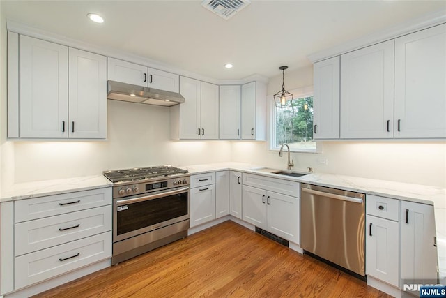 kitchen featuring light wood finished floors, visible vents, appliances with stainless steel finishes, under cabinet range hood, and a sink