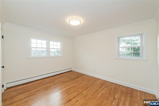 spare room with light wood finished floors, baseboards, ornamental molding, and baseboard heating