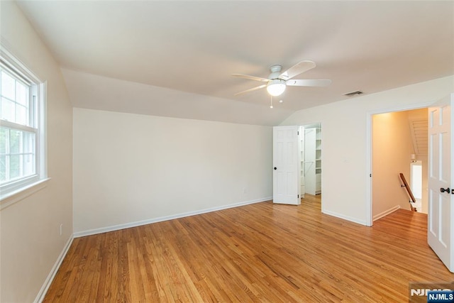 unfurnished bedroom featuring lofted ceiling, baseboards, visible vents, and light wood-style floors