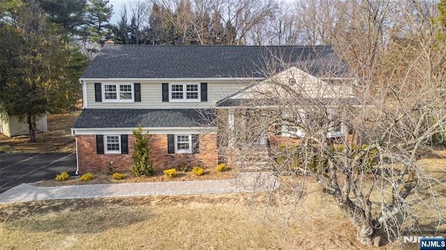 view of front of home with brick siding and roof with shingles