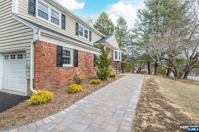 view of side of property featuring a garage and brick siding