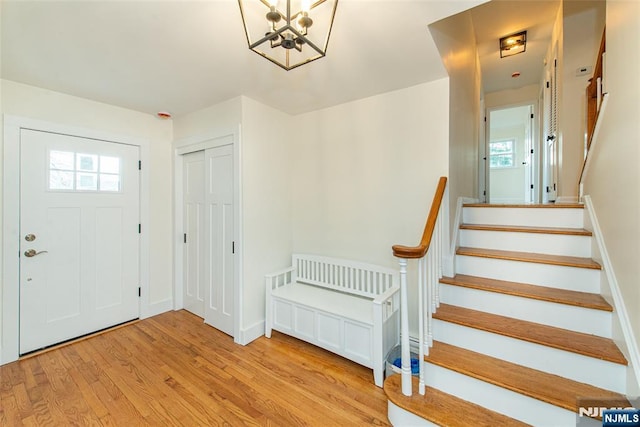 foyer with a healthy amount of sunlight, stairway, baseboards, and wood finished floors