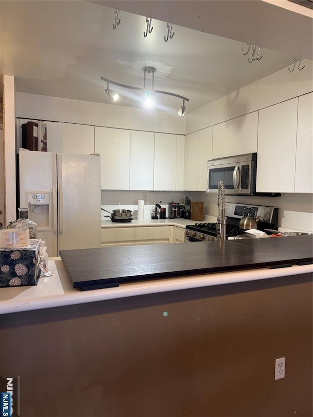 kitchen with appliances with stainless steel finishes, dark countertops, and white cabinetry