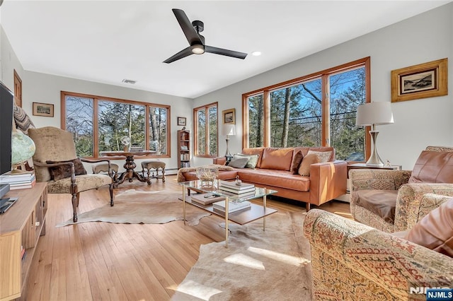 living area with light wood-type flooring, visible vents, and a ceiling fan