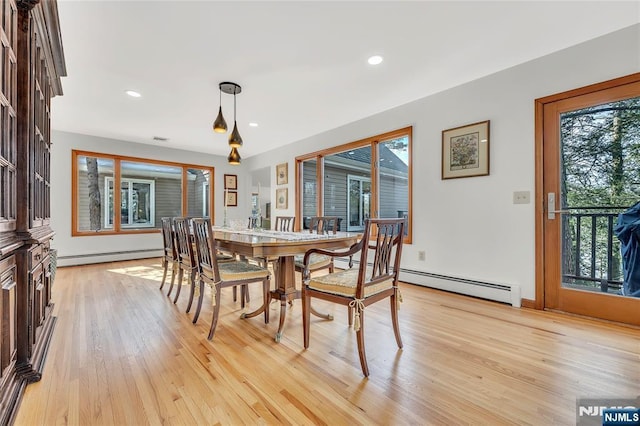 dining room with a healthy amount of sunlight, light wood finished floors, and a baseboard radiator