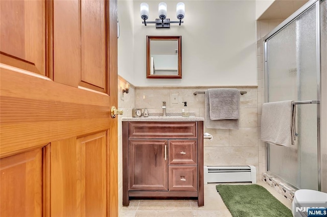 bathroom with tile walls, a baseboard heating unit, a stall shower, vanity, and tile patterned flooring