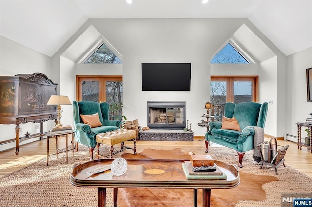 living area with light wood finished floors, baseboards, a glass covered fireplace, french doors, and high vaulted ceiling