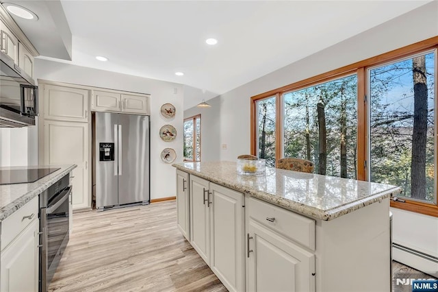 kitchen featuring white cabinets, a kitchen island, light stone counters, and stainless steel appliances