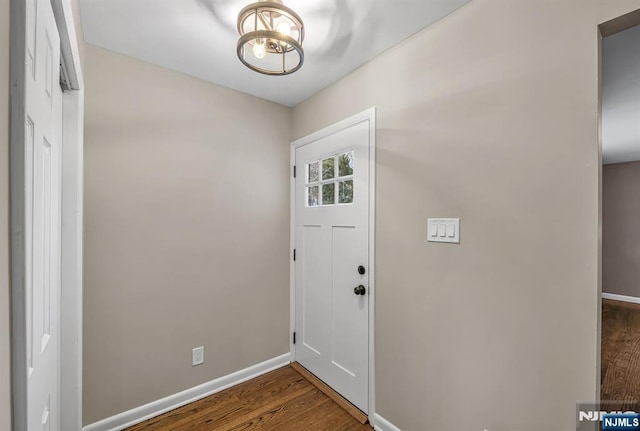 doorway with dark wood-type flooring and baseboards