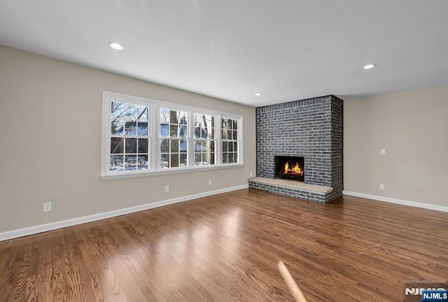 unfurnished living room with recessed lighting, a fireplace, baseboards, and wood finished floors