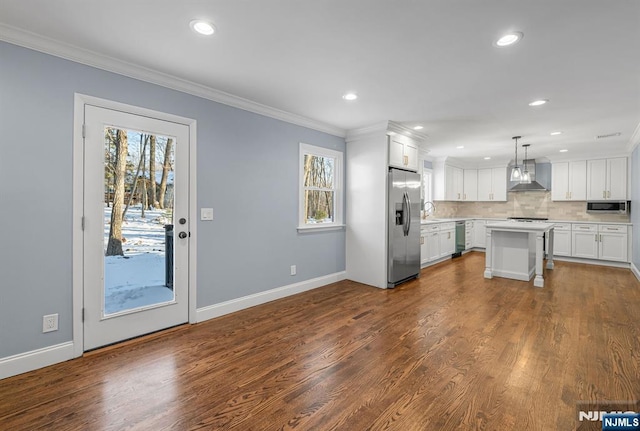 kitchen featuring wall chimney exhaust hood, a kitchen island, decorative light fixtures, light countertops, and white cabinetry