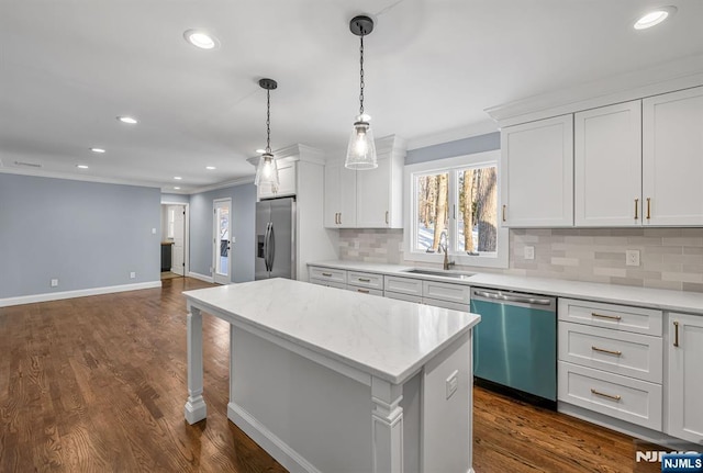 kitchen with a sink, white cabinetry, light countertops, appliances with stainless steel finishes, and a center island