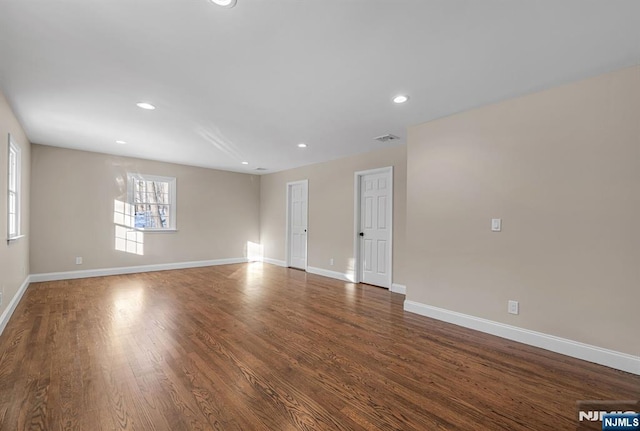 spare room featuring dark wood-type flooring, recessed lighting, visible vents, and baseboards