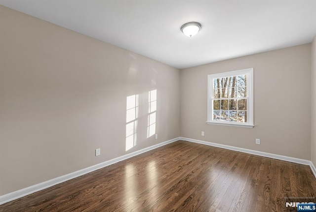 spare room with dark wood-type flooring and baseboards