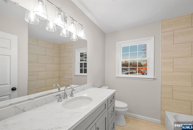 bathroom featuring toilet, baseboards, a bath, and vanity