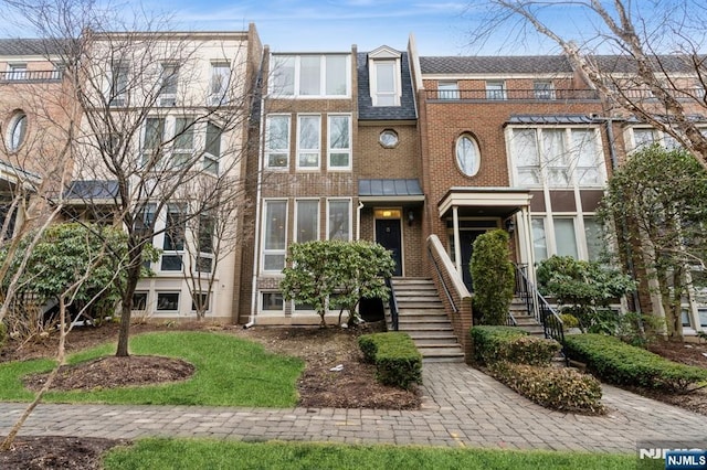 view of property featuring stairs and brick siding