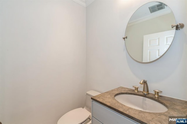 half bath with visible vents, toilet, ornamental molding, and vanity