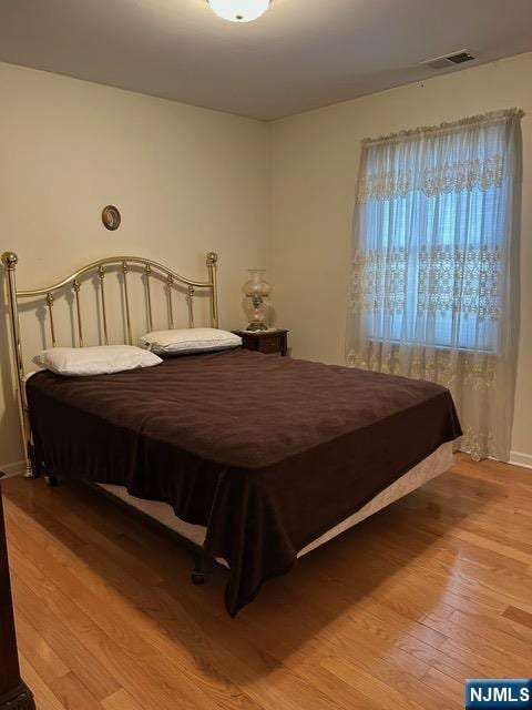 bedroom featuring visible vents and wood finished floors