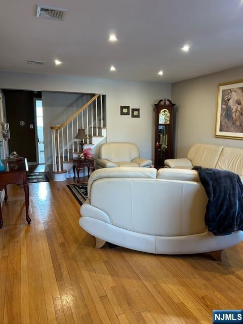 living room with light wood-style flooring, stairs, visible vents, and recessed lighting