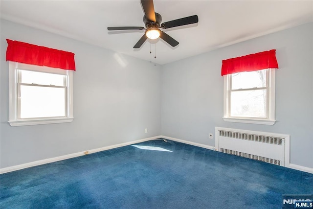 carpeted empty room featuring baseboards, ceiling fan, and radiator