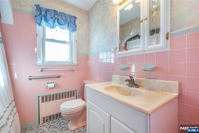 bathroom with toilet, vanity, wainscoting, radiator heating unit, and wallpapered walls