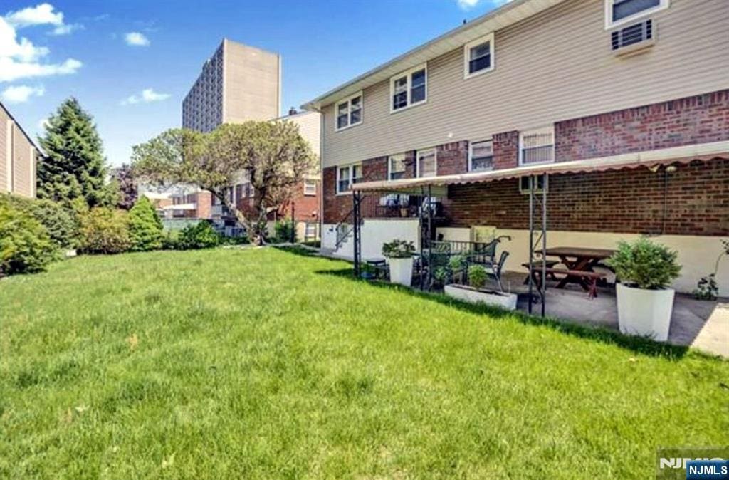 back of property with a yard, brick siding, and a patio