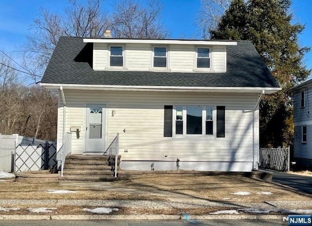 view of front of house featuring a shingled roof, entry steps, and fence