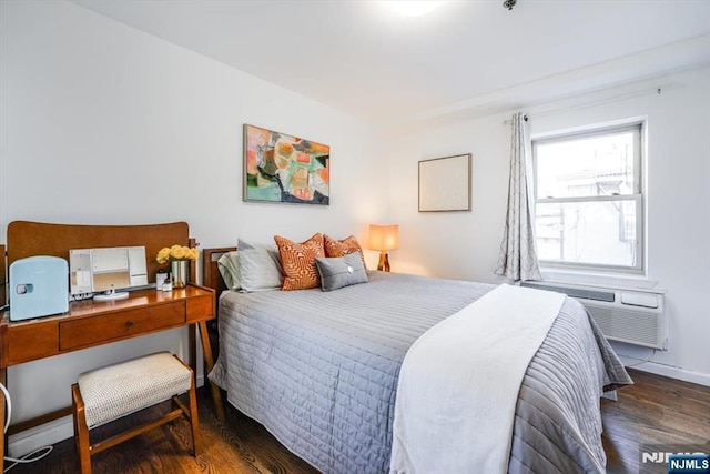 bedroom featuring a wall mounted air conditioner, baseboards, and wood finished floors