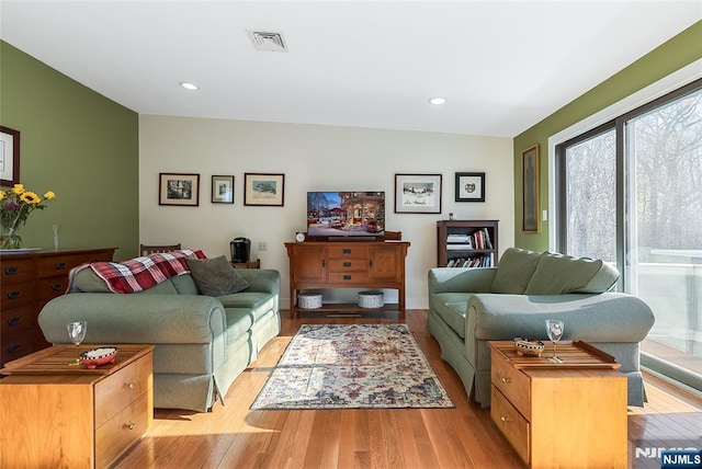 living room with light wood-style floors, visible vents, and recessed lighting