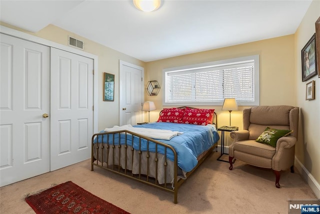 carpeted bedroom featuring visible vents and multiple closets