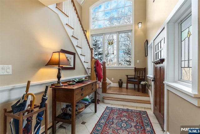 interior space featuring stairs, a high ceiling, and light tile patterned flooring