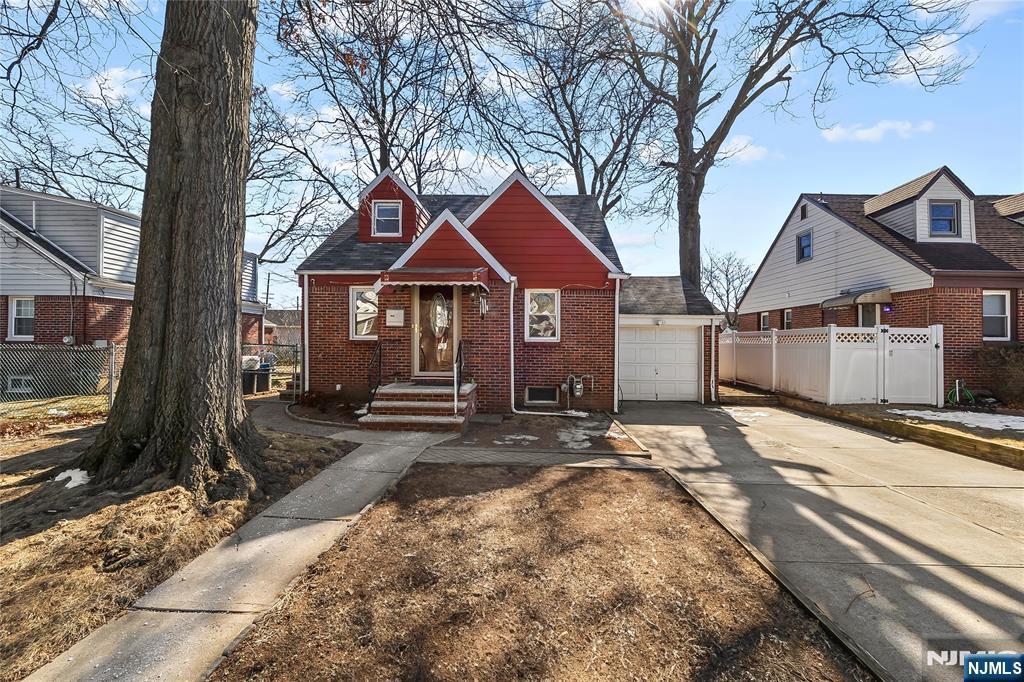 view of front of property with concrete driveway, brick siding, an attached garage, and fence