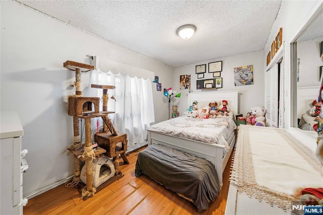 bedroom with a closet, a textured ceiling, and wood finished floors