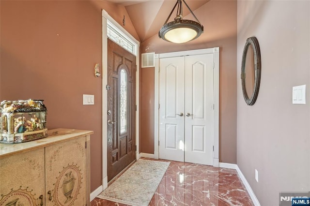 foyer featuring lofted ceiling, marble finish floor, visible vents, and baseboards