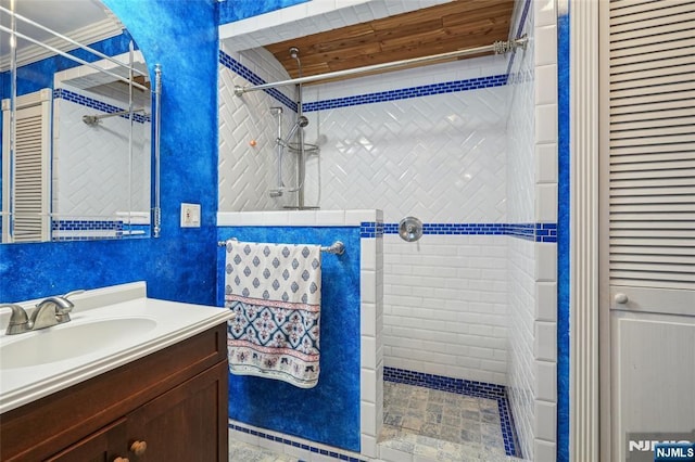 full bathroom featuring a walk in shower, a textured wall, ornamental molding, and vanity