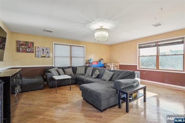 living room featuring a chandelier, visible vents, light wood-style flooring, and baseboards