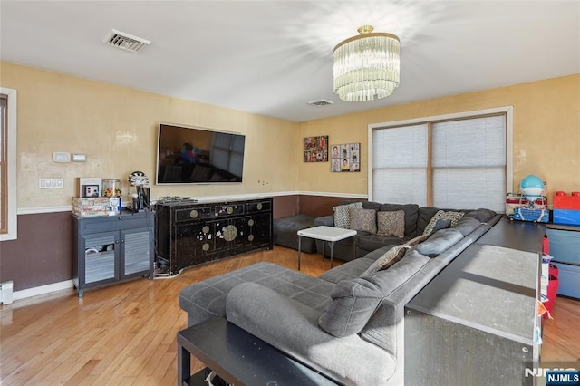 living room with light wood finished floors, baseboards, visible vents, and a chandelier