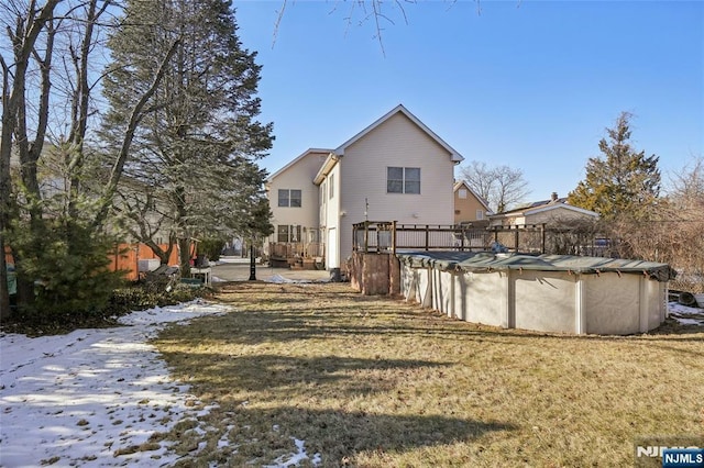 back of property with a covered pool and a lawn