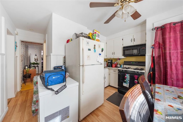 kitchen with white cabinets, gas range, freestanding refrigerator, light countertops, and black microwave