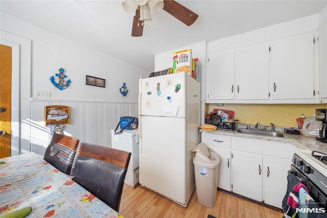 kitchen with white appliances, light wood-style floors, white cabinets, and a sink